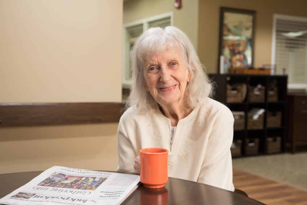 Resident Smiling With Coffee And Newspaper