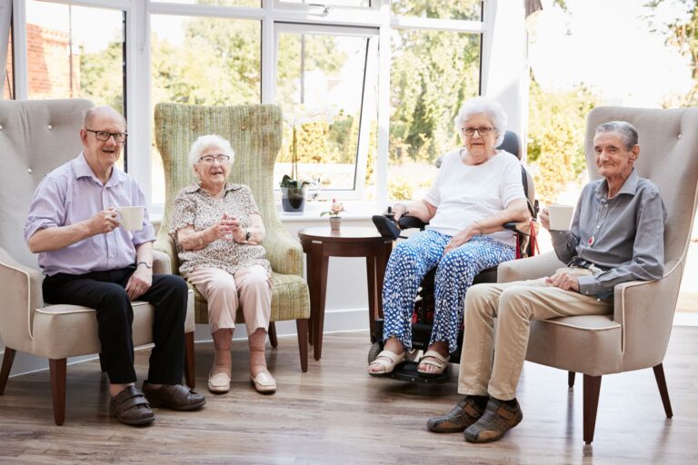 group of 4 seniors sitting in a sun room sipping tea