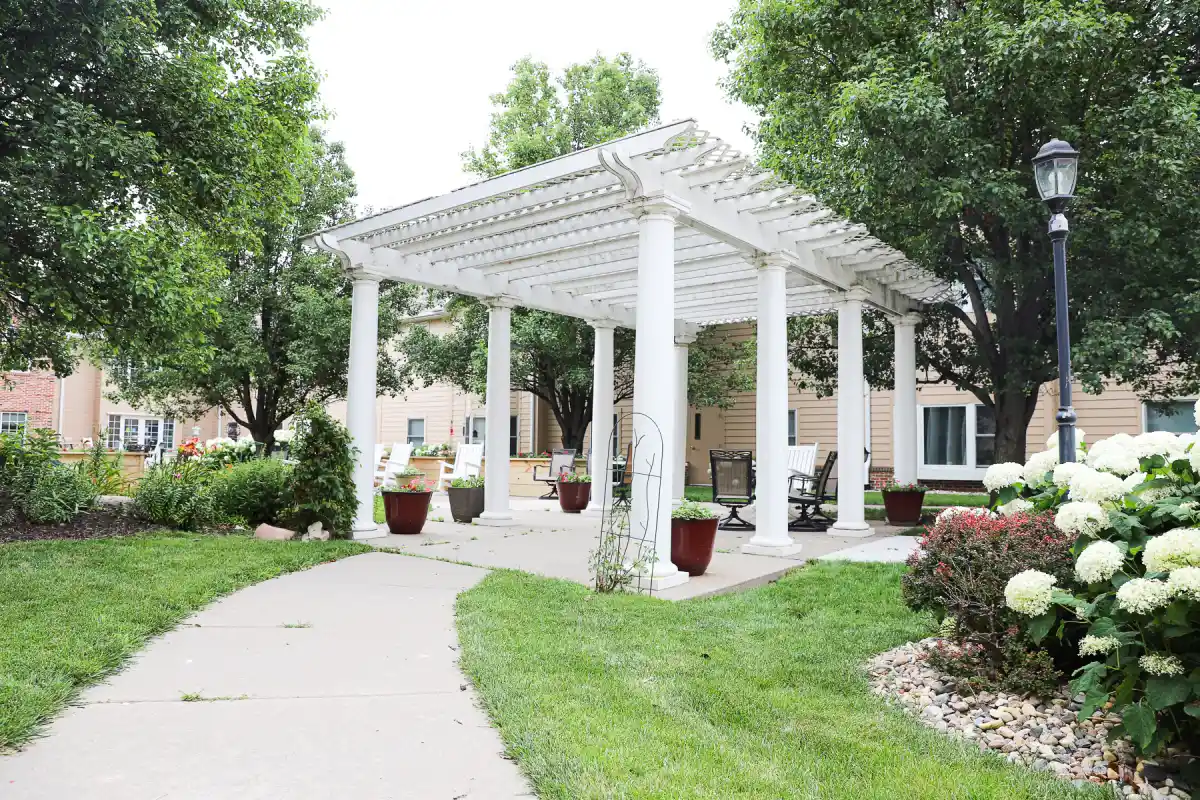 The Heritage at Fox Run assisted living secure courtyard with white pergola and chairs to enjoy the beautiful outdoor space