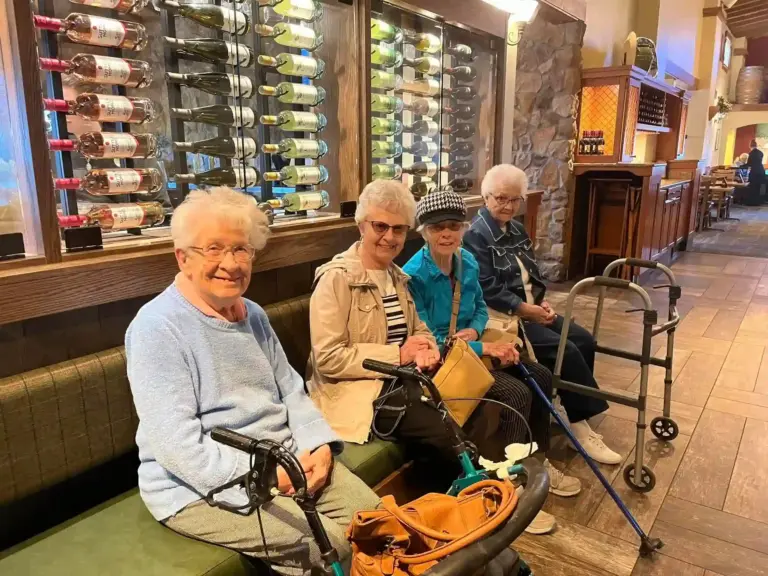 A group of seniors sit on a bench from The Heritage at Shalimar Gardens senior living community