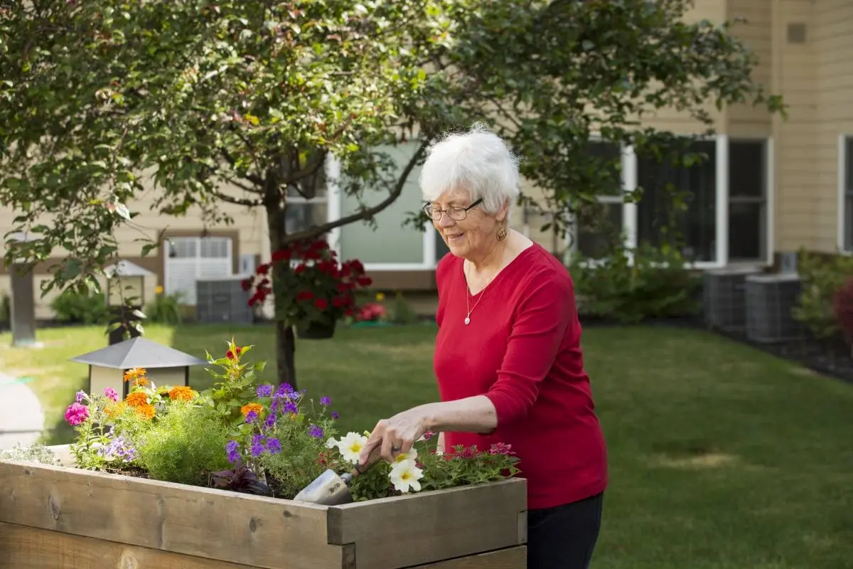 A resident tending to a planter garden outside in the courtyard