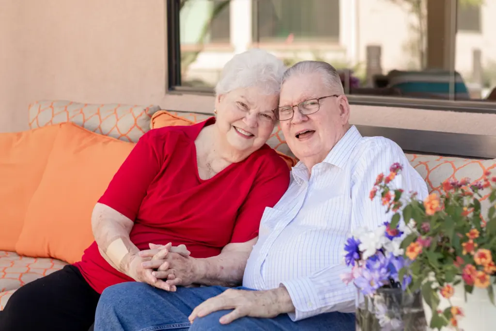 A couple embraces on couch at Orchard Pointe at Terrazza retirement community