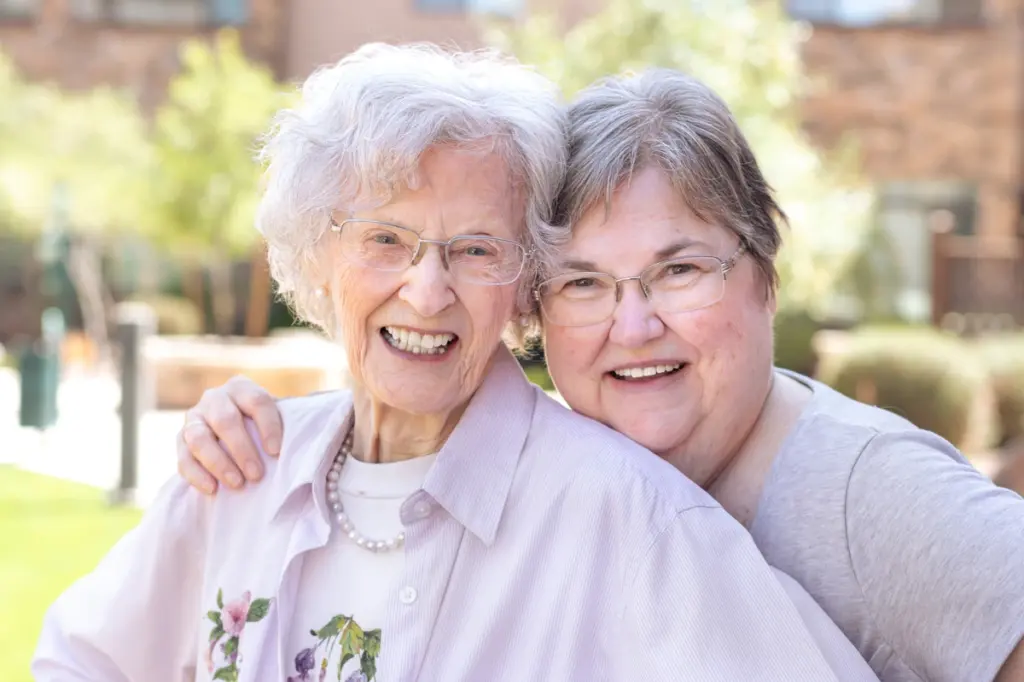 Orchard Pointe at Arrowhead senior women embracing in courtyard