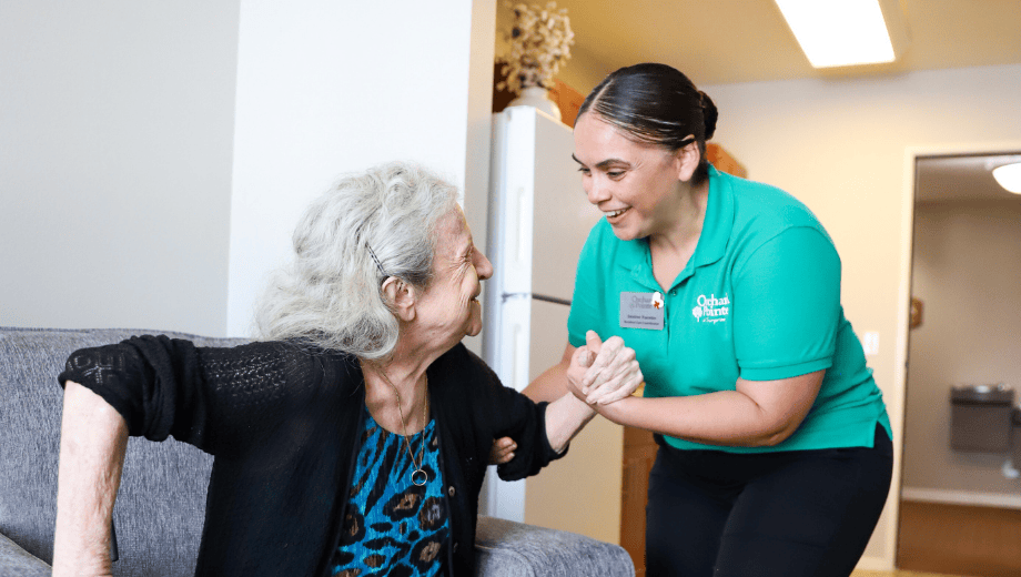 ai caregiver in assisted living helps a resident rise from a chair